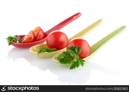 Fresh tomatoes and parsley leaves on ceramic spoons.