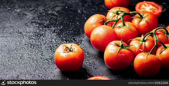 Fresh tomatoes and tomato slices on the table. On a black background. High quality photo. Fresh tomatoes and tomato slices on the table.