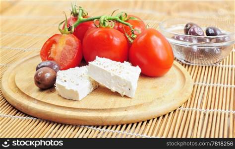 Fresh tomatoes, olives and white cheese on wooden board