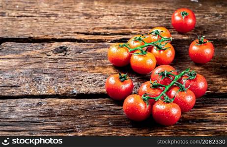 Fresh tomatoes on a branch on the table. On a wooden background. High quality photo. Fresh tomatoes on a branch on the table.