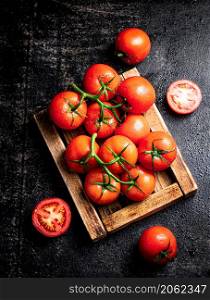 Fresh tomatoes on a wooden tray. On a black background. High quality photo. Fresh tomatoes on a wooden tray.