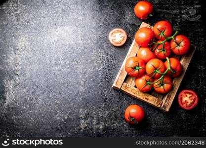 Fresh tomatoes on a wooden tray. On a black background. High quality photo. Fresh tomatoes on a wooden tray.