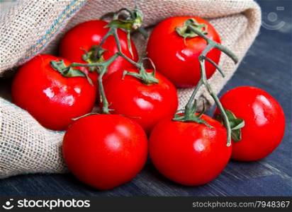 fresh tomatoes on burlap sack on wood