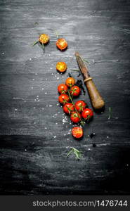 Fresh tomatoes with a knife . On black rustic background.. Fresh tomatoes with a knife .