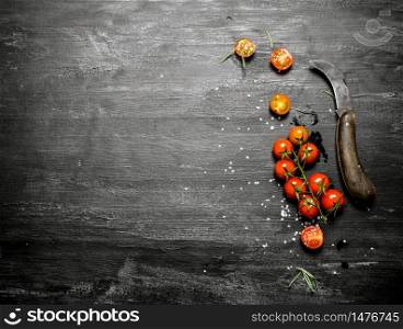 Fresh tomatoes with a knife . On black rustic background.. Fresh tomatoes with a knife .