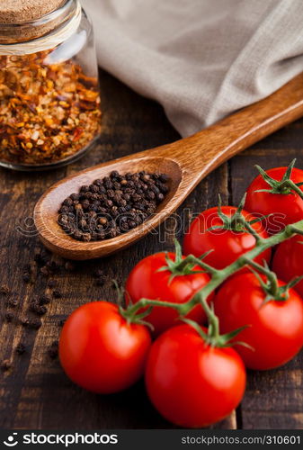 Fresh tomatoes with basil and spoon with pepper on grunge wooden board. Jar with spices