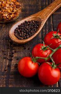 Fresh tomatoes with basil and spoon with pepper on grunge wooden board. Jar with spices