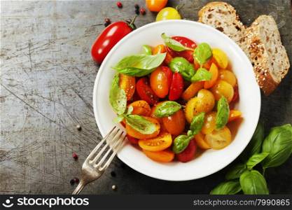 Fresh tomatoes with basil leaves in a bowl on vintage background.