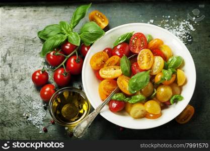 Fresh tomatoes with basil leaves in a bowl on vintage background.