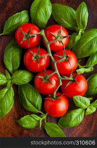 Fresh tomatoes with basil on wooden board. Closeup