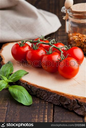 Fresh tomatoes with basiland spices jar on grunge wooden background