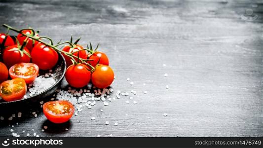Fresh tomatoes with coarse salt . On black rustic background.. Fresh tomatoes with coarse salt .