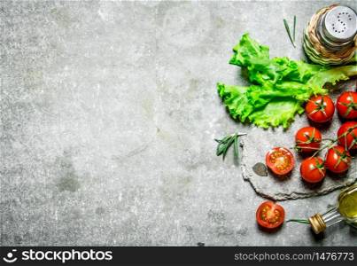 Fresh tomatoes with lettuce and olive oil. On a stone background. . Fresh tomatoes with lettuce and olive oil.