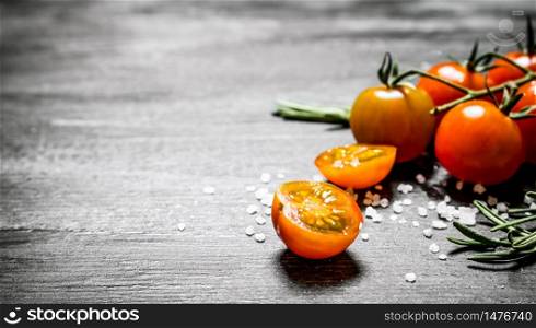 Fresh tomatoes with salt and rosemary. On black rustic background.. Fresh tomatoes with salt and rosemary.