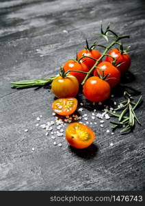 Fresh tomatoes with salt and rosemary. On black rustic background.. Fresh tomatoes with salt and rosemary.