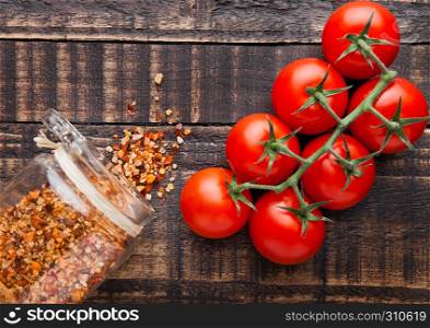 Fresh tomatoes with spices jar on grunge wooden background