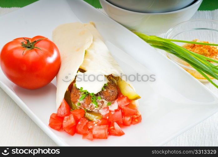 fresh traditional falafel wrap on pita bread with fresh chopped tomatoes