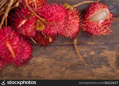 fresh tropical rambutan fruits over rustic wood table