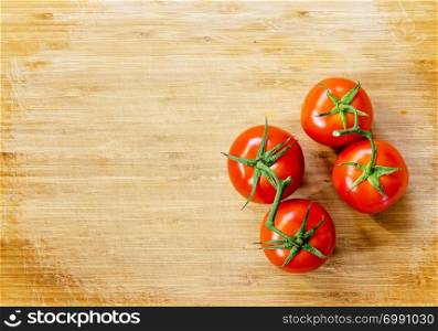 Fresh truss tomatoes sitting on a wooden board background