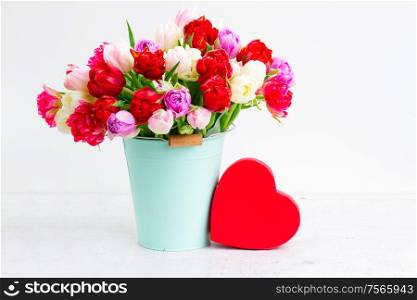 Fresh tulips flowers in vase with red heart gift present box on white background. Fresh tulips flowers with heart