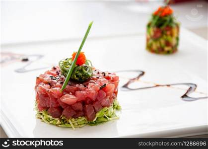 Fresh Tuna tartare sesame seaweed and green salad and balsamic reduction sauce and tropical fruits salsa in white plate