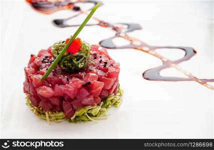 Fresh Tuna tartare sesame seaweed and green salad and balsamic reduction sauce and tropical fruits salsa in white plate