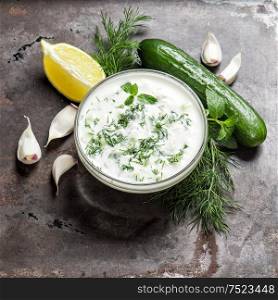 Fresh tzatziki yogurt sauce. Herbs and vegetables. Food background