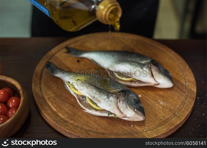 Fresh uncooked dorado with lemon, herbs, oil and spices ready for preparing