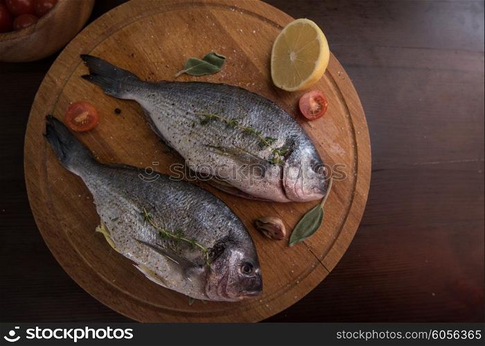 Fresh uncooked dorado with lemon, herbs, oil and spices ready for preparing