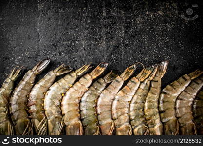 Fresh uncooked raw shrimp. On a black background. High quality photo. Fresh uncooked raw shrimp. On a black background.