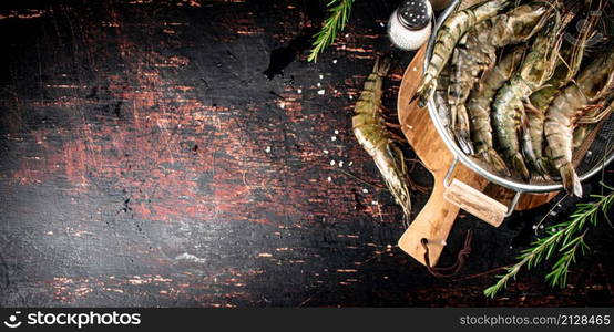 Fresh uncooked shrimp in a colander. On rustic dark background. High quality photo. Fresh uncooked shrimp in a colander.