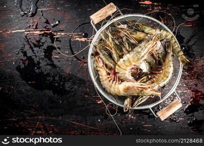 Fresh uncooked shrimp in a colander. On rustic dark background. High quality photo. Fresh uncooked shrimp in a colander.