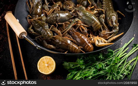 Fresh uncooking crayfish in a pot of lemon and parsley. Against a dark background. High quality photo. Fresh uncooking crayfish in a pot of lemon and parsley.