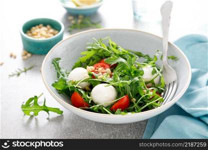 Fresh vegetable Caprese salad with arugula, tomato, pine nuts and mini mozzarella cheese