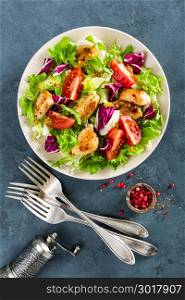 Fresh vegetable salad bowl of tomatoes, cucumbers, italian mix, lettuce and grilled chicken breast on table. Fried chicken meat, fillet with salad. Healthy food. Diet dinner or lunch menu. Flat lay. View from above