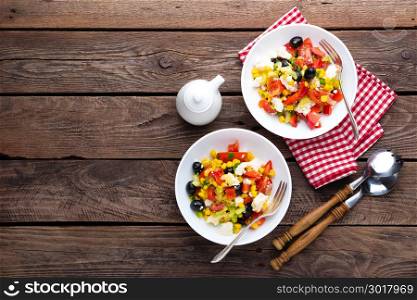 Fresh vegetable salad bowls of tomatoes, corn, pepper, olives, celery, green onion and feta cheese. Healthy food. Diet dinner or lunch menu. Salad plate on table. Flat lay. Top view