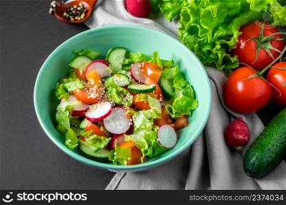 Fresh vegetable salad in a ceramic bowl on a gray background. Seasonal summer dish of tomatoes, cucumbers and radishes.. Fresh vegetable salad in a ceramic bowl on gray background. Seasonal summer dish of tomatoes, cucumbers and radishes.