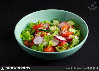 Fresh vegetable salad in a ceramic bowl on a gray background. Seasonal summer dish of tomatoes, cucumbers and radishes.. Fresh vegetable salad in a ceramic bowl on gray background. Seasonal summer dish of tomatoes, cucumbers and radishes.