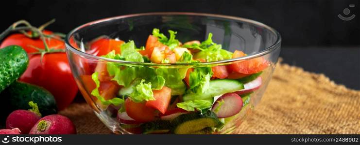 Fresh vegetable salad in a glass bowl on a dark background. Vegan organic food, seasonal summer dish. Banner format.. Fresh vegetable salad in a glass bowl on dark background. Vegan organic food, seasonal summer dish.