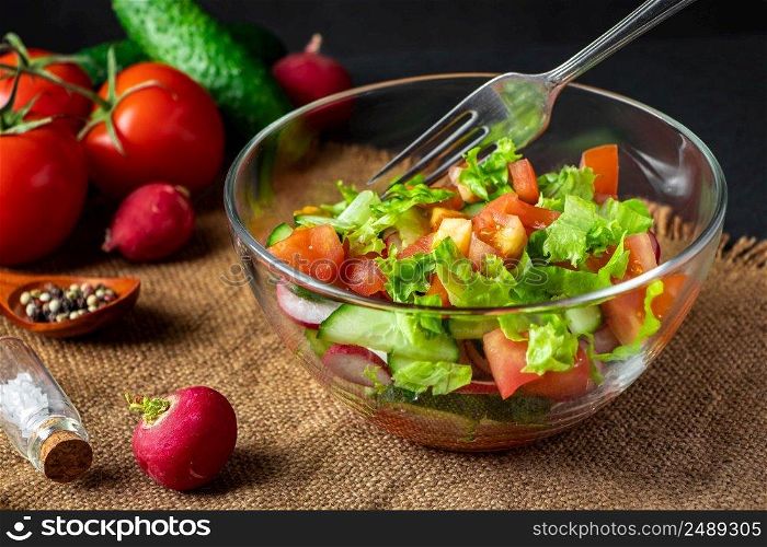 Fresh vegetable salad in a glass bowl on a dark background. Vegan organic food, seasonal summer dish.. Fresh vegetable salad in a glass bowl on dark background. Vegan organic food, seasonal summer dish.