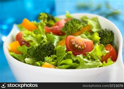 Fresh vegetable salad made of cherry tomato, broccoli, yellow bell pepper and lettuce (Selective Focus, Focus on the tomato and the broccoli in the front). Light Fresh Vegetable Salad