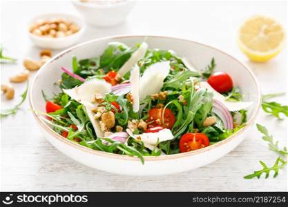 Fresh vegetable salad with arugula, tomato, onion, parmesan cheese and cashew nuts