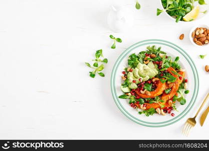 Fresh vegetable salad with lambs lettuce, baked butternut squash or pumpkin, avocado, pomegranate, cashew and almond nuts. Healthy vegetarian food concept. Top view