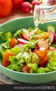 Fresh vegetable salad with olive oil in ceramic bowl on a wooden background. Seasonal summer dish of tomatoes, cucumbers and radishes.. Fresh vegetable salad with olive oil in ceramic bowl on wooden background. Seasonal summer dish of tomatoes, cucumbers and radishes.