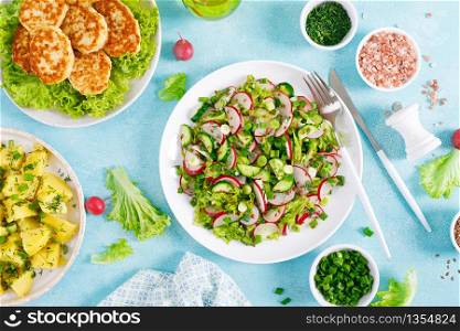 Fresh vegetable salad with radish, lettuce and cucumber, boiled new potato with butter, dill and green onion and fried chicken meat cutlets for lunch
