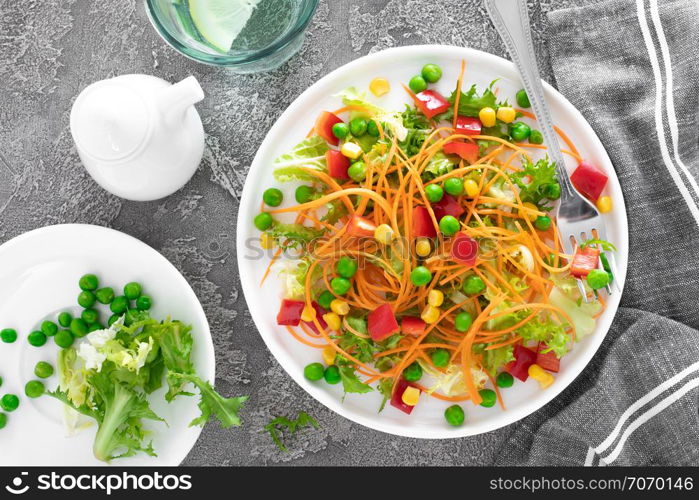 Fresh vegetable salad with raw carrot, green peas, corn, sweet pepper and lettuce. Healthy vegan, vegetarian lunch menu. Top view