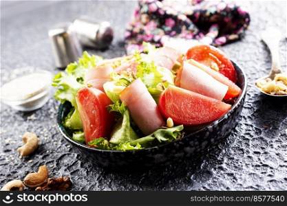 Fresh vegetable salad with slices of ham , cherry tomatoes lettuce leaves. Ham salad. Take away food.