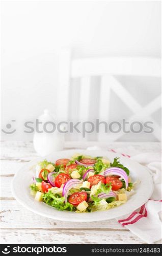 Fresh vegetable salad with tomatoes, lettuce, onion and cheese on white wooden background. Healthy vegetarian food. Top view