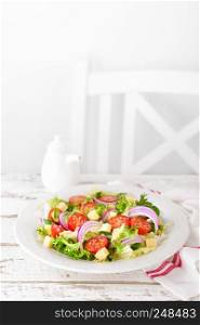 Fresh vegetable salad with tomatoes, lettuce, onion and cheese on white wooden background. Healthy vegetarian food. Top view