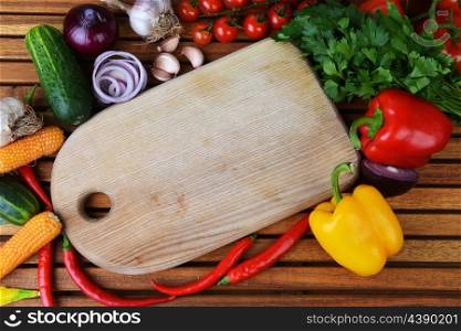 fresh vegetables and cutting board on wooden background
